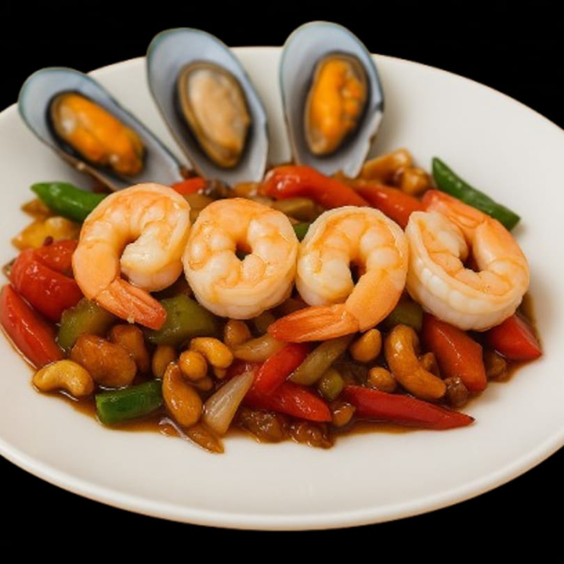 Thai stir-fry with shrimp, mussels, cashews, and colorful vegetables on a white plate.